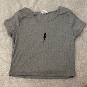 A gray cropped shirt with a black lightning bolt and is in good condition